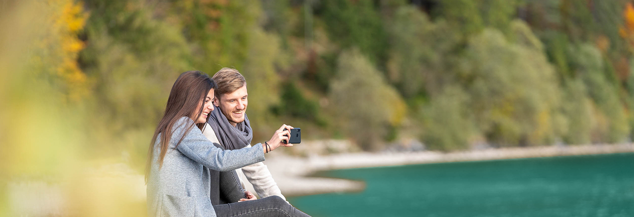 Frau und Mann sitzen am Steg am See