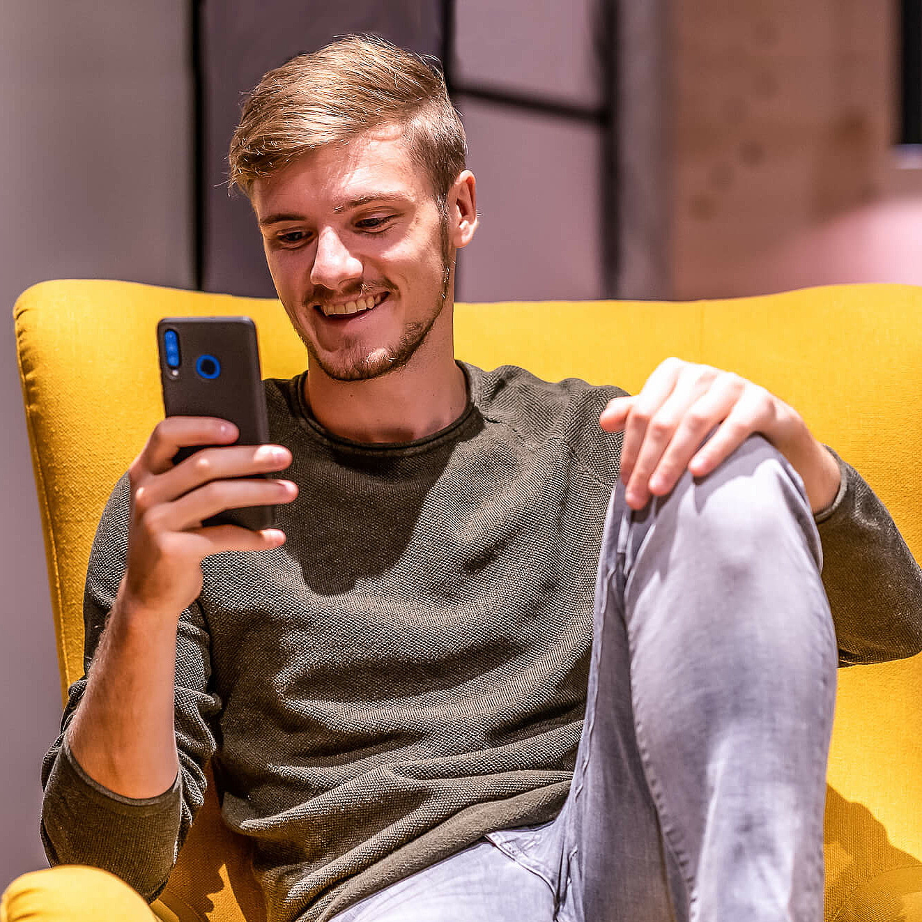 Mann auf Sessel mit Smartphone in der Hand