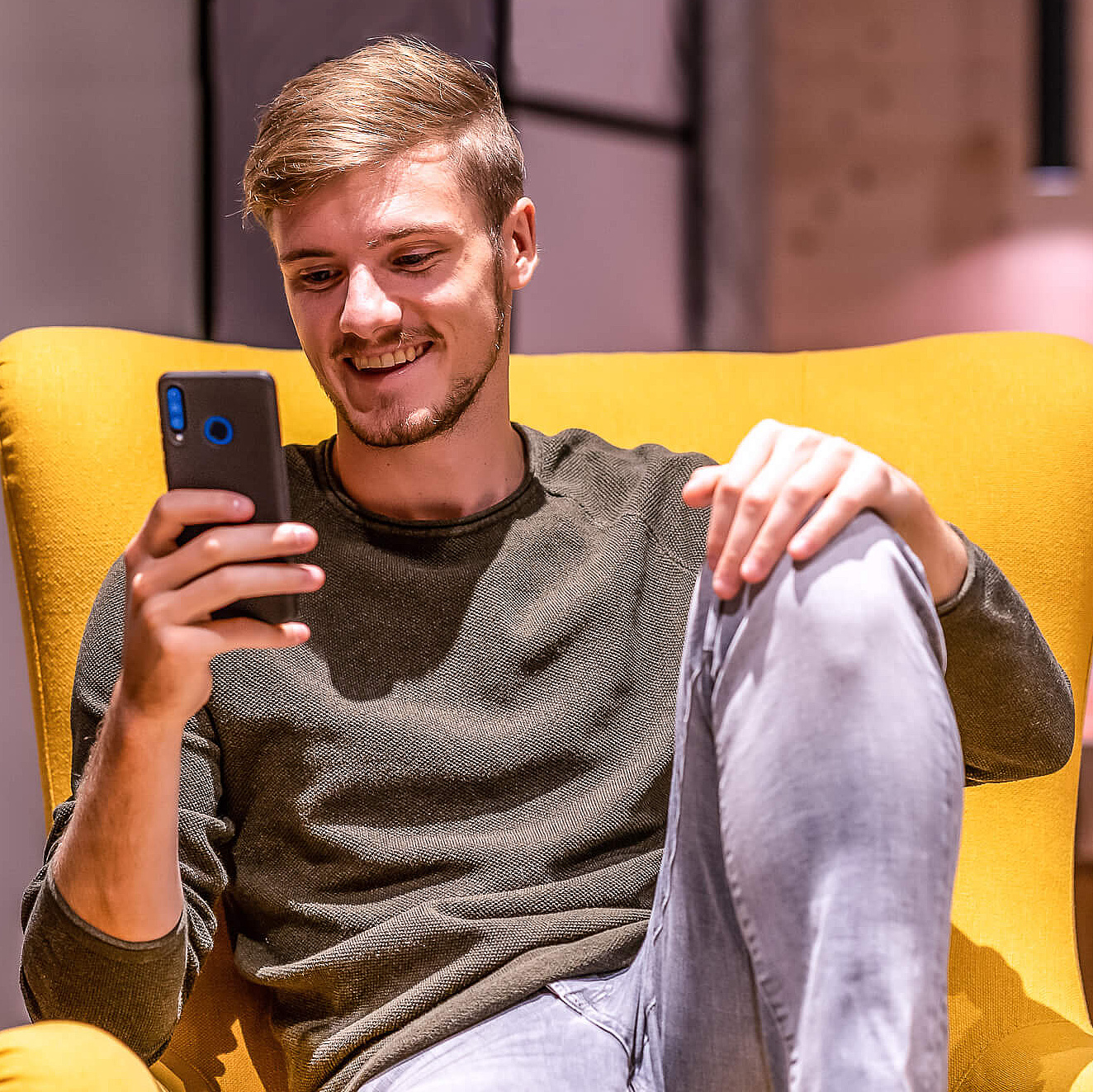 Mann auf Sessel mit Smartphone in der Hand