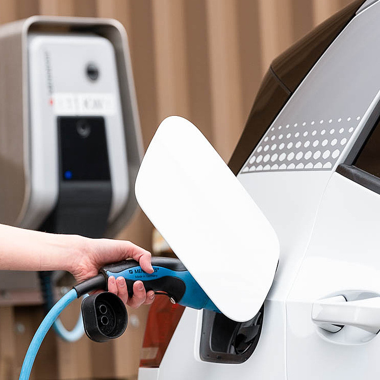 Frau lädt Elektroauto