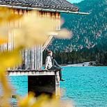 Mann sitzt bei Bootshaus am See