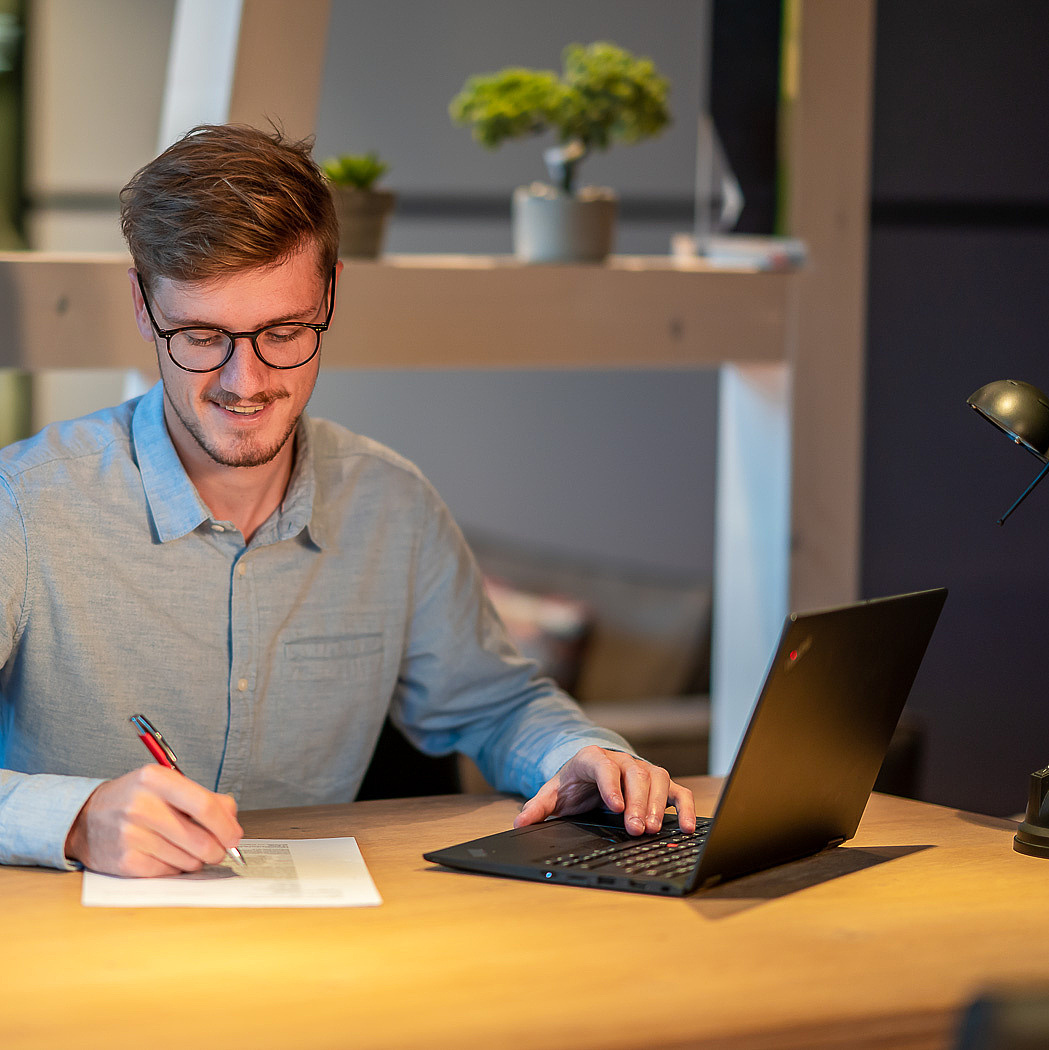 Mann sitzt mit Laptop am Tisch