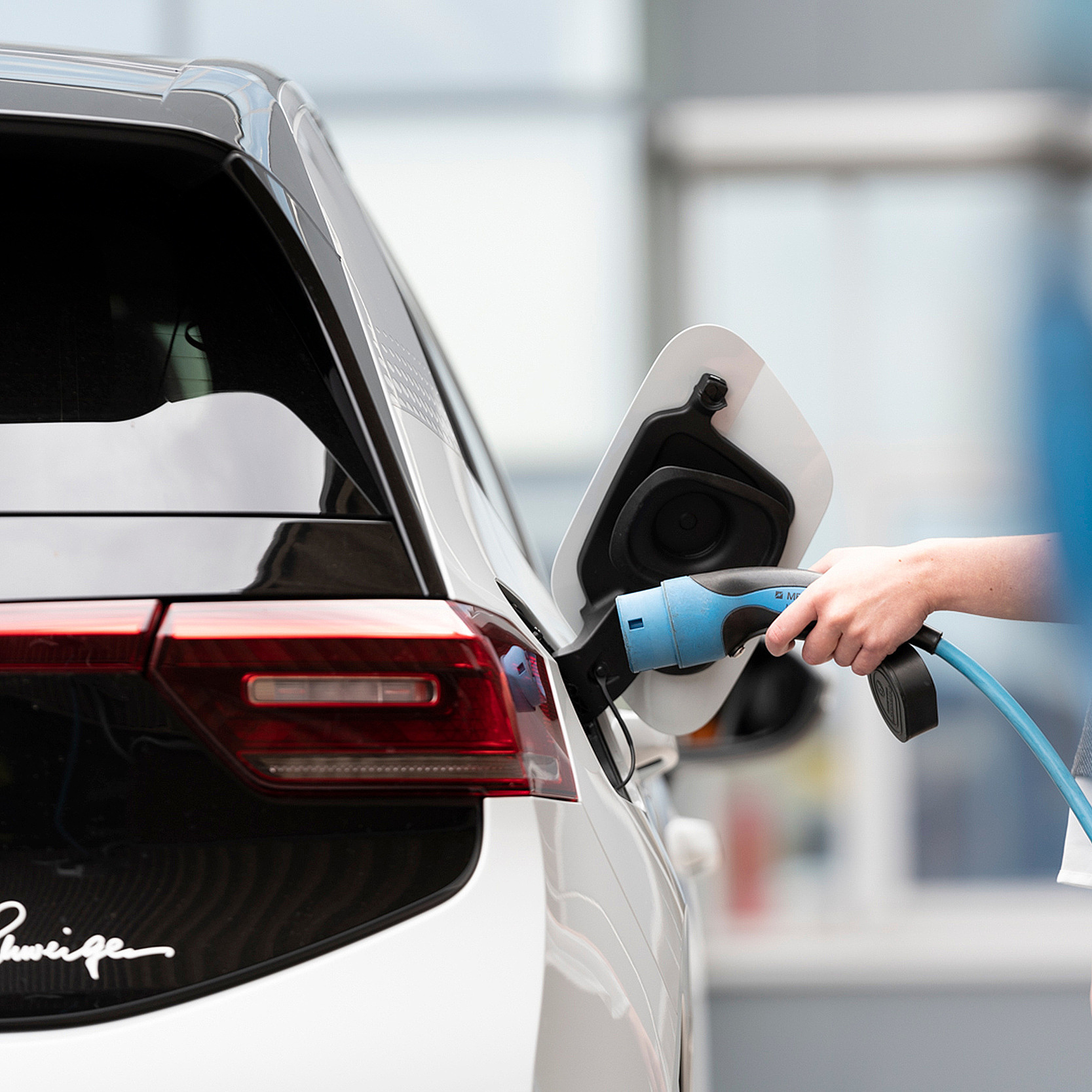 Frau lädt Elektroauto an Ladestation