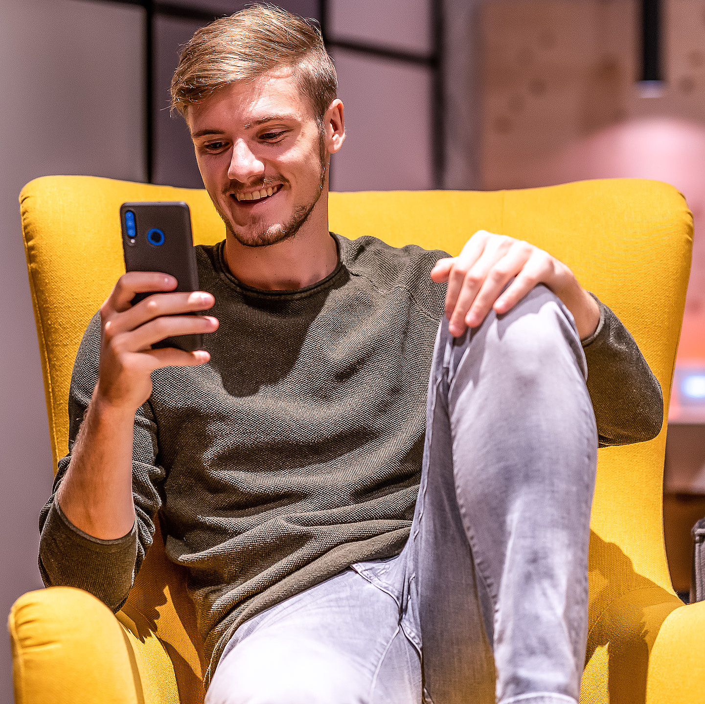 Mann auf Sessel mit Smartphone in der Hand