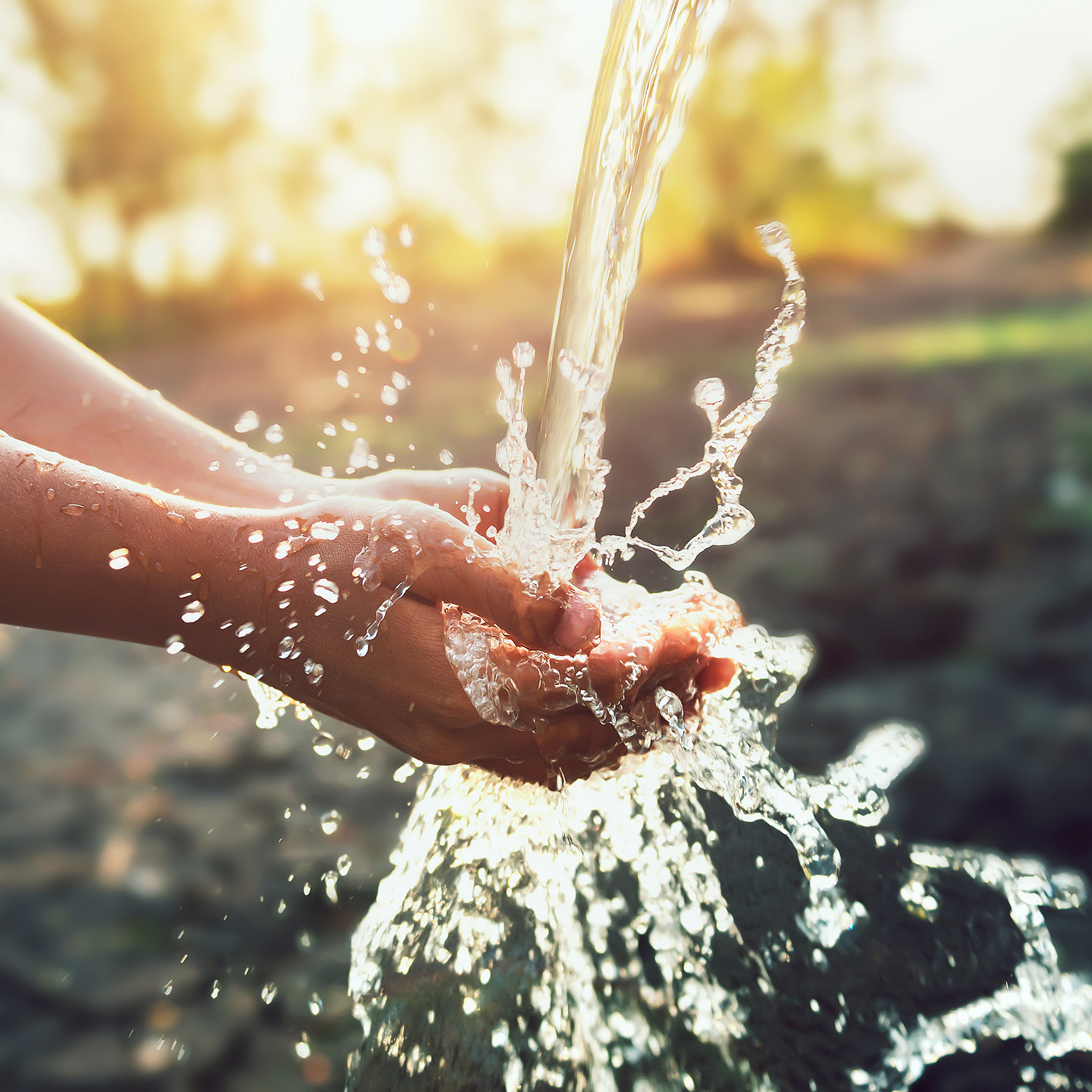 Hände fangen klares Wasser aus einer Quelle oder Leitung im Freien