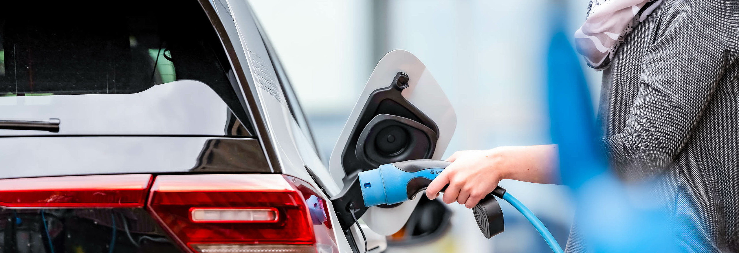Frau lädt Elektroauto