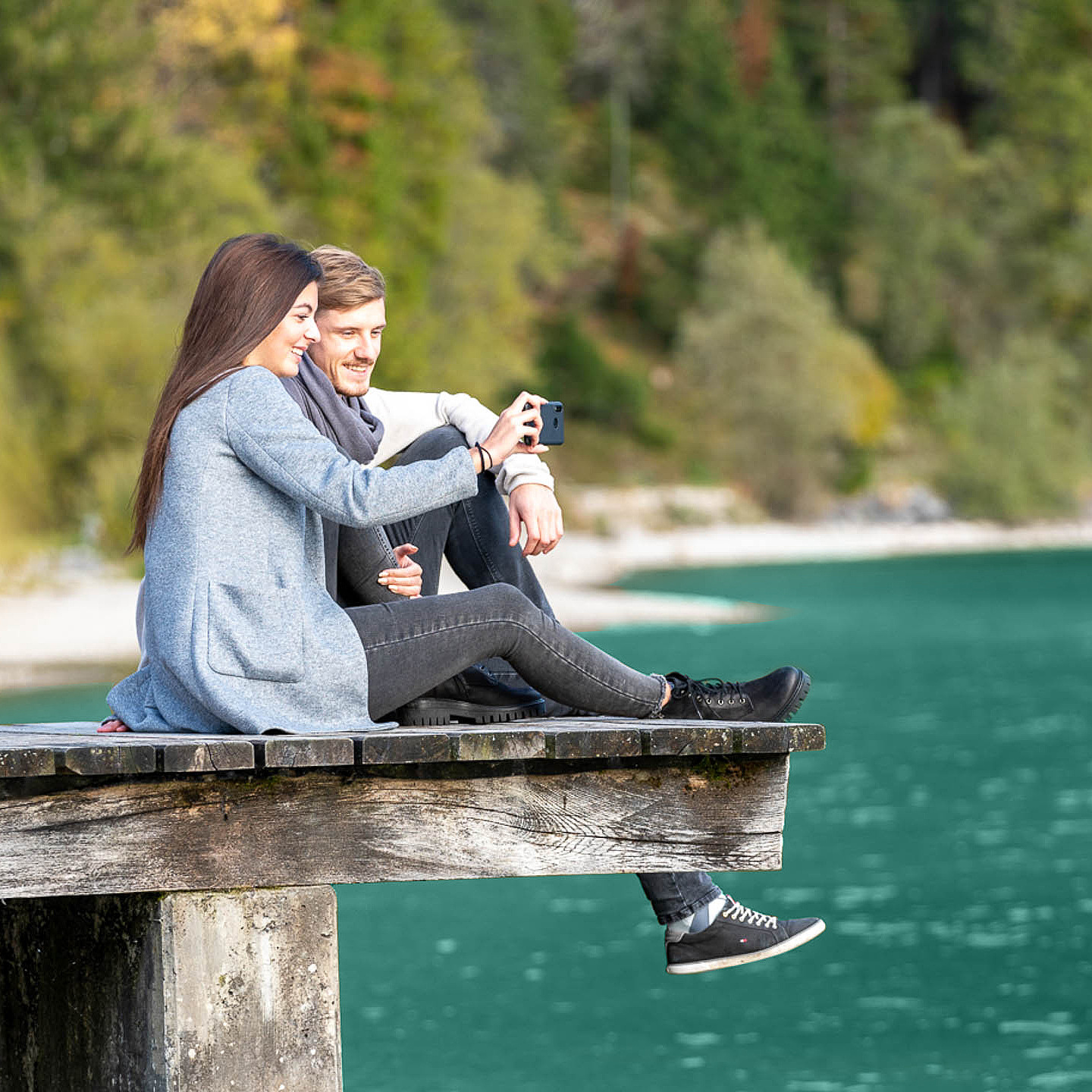 Frau und Mann sitzen am Steg am See