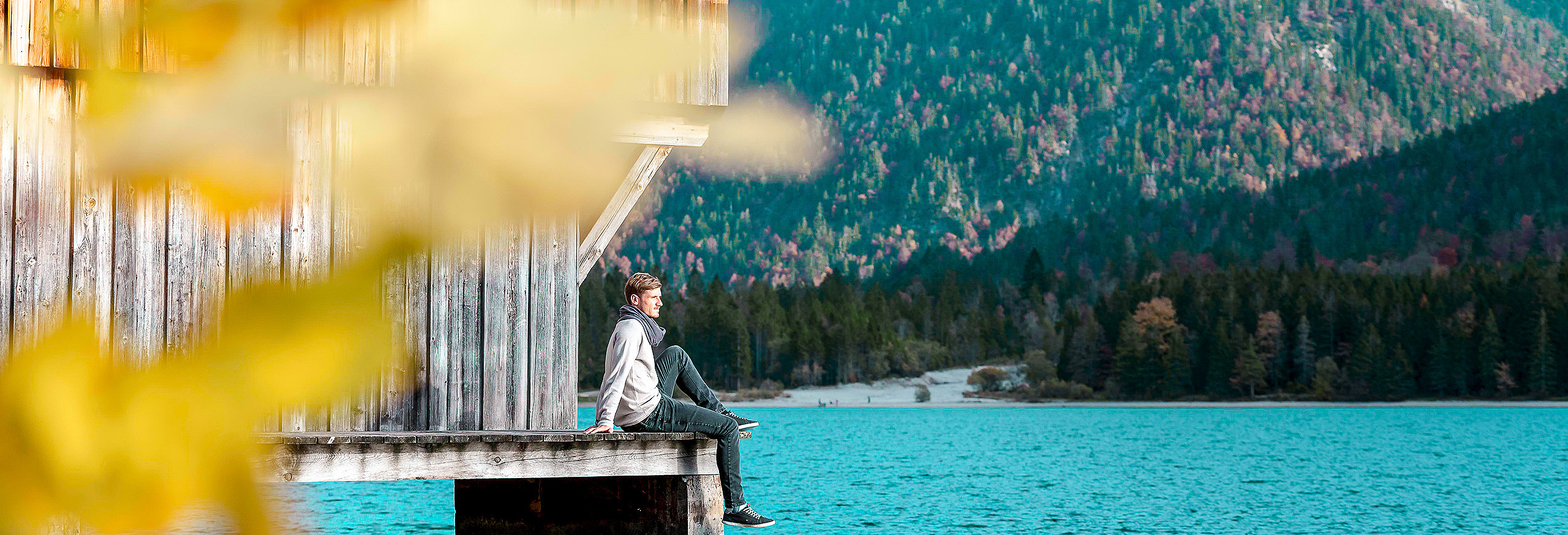 Mann sitzt bei Bootshaus am See