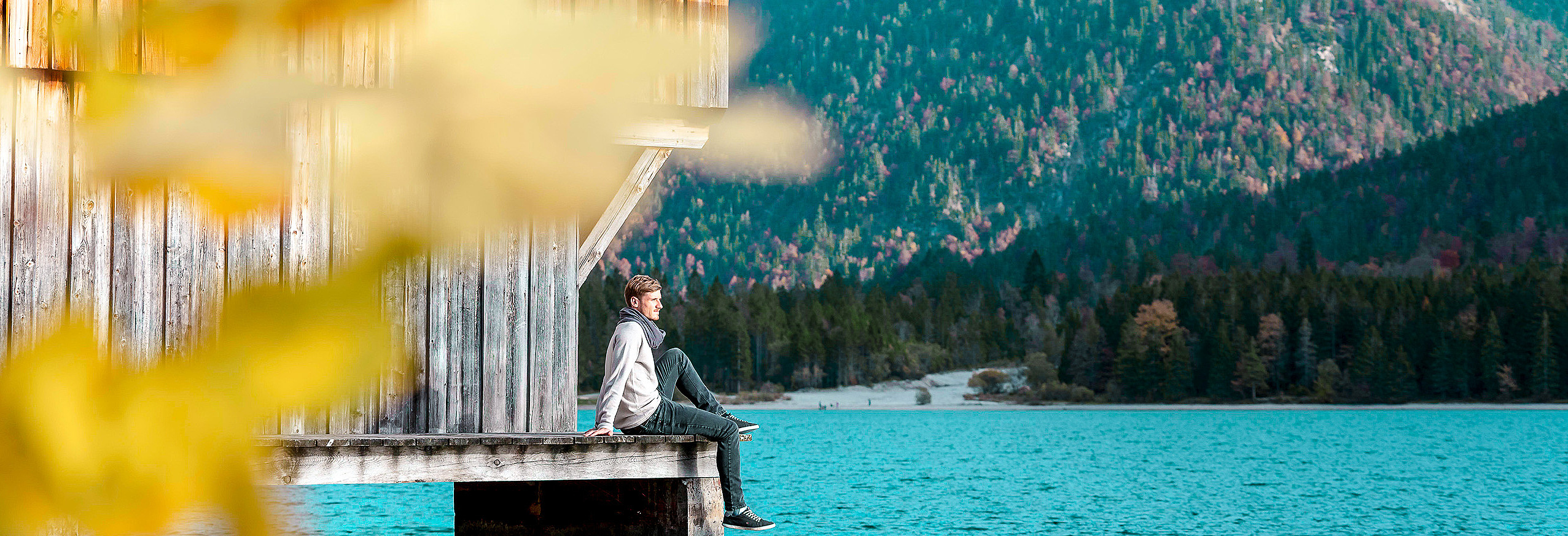 Mann sitzt bei Bootshaus am See