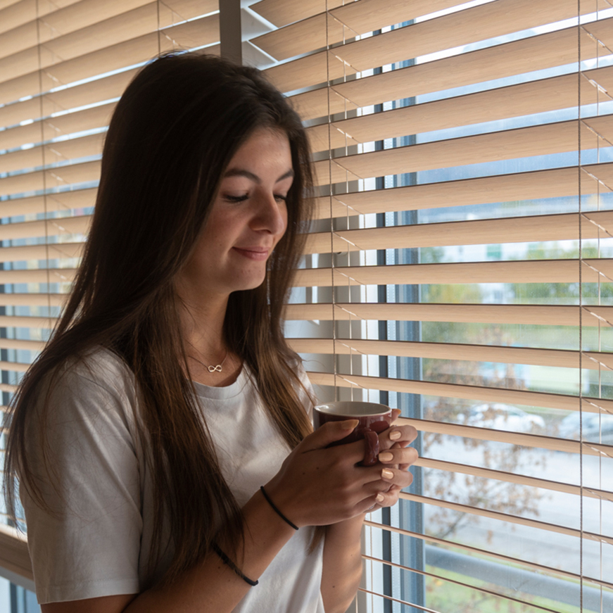 Frau steht am Fenster mit Beschattung