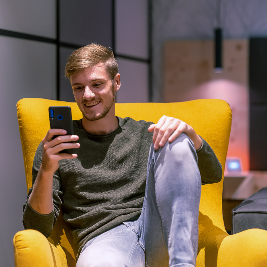 Mann auf Sessel mit Smartphone in der Hand