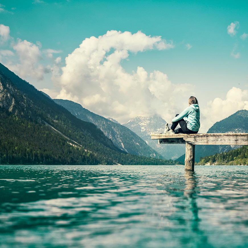 Frau sitz auf einem Steg am See